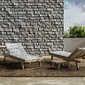 Outdoor Wooden Lounge Chairs With Light Cushions By Stone Wall And Woven Rug