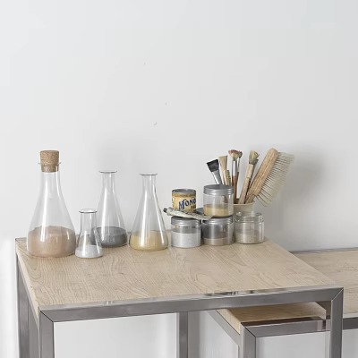 Various Ceramic Vessels Arranged On Light Wooden Table With Art Brushes And Metal Cans 3d model