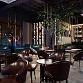 Cozy Bar Interior Featuring Leather Chairs Round Tables Hanging Plants And City Night View