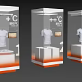 Corporate Exhibition Hall with Transparent Display Cases Featuring White T-Shirts Digital Screens and Orange Bases