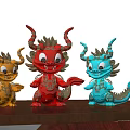 Three Carved Dragon Sculptures In Red Orange Blue With Golden Decorations On Wooden Table