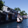 Ancient Architecture Along Waterway With White Walls Gray Tiles Boat Red Lanterns Pink Cherry Trees