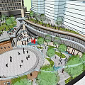 Modern Commercial Street Scene with Tall Glass Building Shops Vehicles Pedestrians and Urban Greenery
