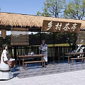 Rural Landscape Featuring Thatched Roof Tea Pavilion With Wooden Tables Benches And Surrounding Trees