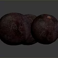 Three Dark Red Round Textured Fruits With Orange Tops On Dark Background