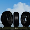 Different Car Tires With Rims Displayed Outdoors On Green Grass Under Blue Sky