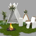 Outdoor Camping Setting with White Tepee Flower Arrangements Bonfire and Chair on Green Grass