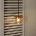 Glass Pendant Light Emitting Warm Glow Beside White Window Blinds in Interior