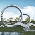 Modern White Sculpture With Circular Rings And Wavy Structures In Grass Field By Water Pond