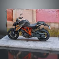 Sporty Black and Orange Motorcycle Displayed On Gray Platform With Red Pink Wall Background