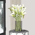 White Calla Lilies Arranged In Transparent Glass Vase On Black Table