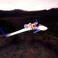 White And Purple Aircraft On Rocky Terrain With Green Vegetation