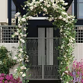 Residential Landscape With Iron Gate Flower Arch White Flowers Green Vines And Surrounding Colorful Plants