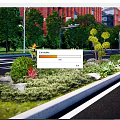 Colorful Roadside Flower Bed Featuring Various Flowers Plants Trees And Red Brick Buildings