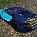 Shiny Blue Bugatti Sports Car With Sleek Design Parked On Gravel Ground With Fallen Leaves
