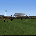 Soccer Players Playing Football Match on Green Field at Stadium with Spectators and Lighting Towers