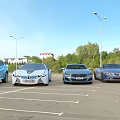 Luxury Sports Cars Parked In Urban Parking Lot With Street Lamps And Church Dome