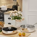 Stainless Steel Cookware With Lids In Bright Kitchen Featuring Fresh Flowers And Coffee Maker