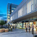 Modern Commercial Street With Modern Buildings Storefronts Pedestrians And Evening Lighting