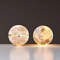 Pair of Spherical Floor Lamps with Moon Surface Texture Illuminated and Dimmed on White Tabletop