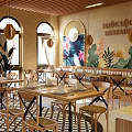 Tropical Floral Mural Restaurant Interior With Arched Windows Pendant Lights And Wooden Tables Chairs