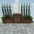 Decorative Garden Planters With Tall Green Plants Pink Flowers Against White Fence Stone Pavement