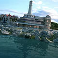Scenic White Lighthouse With Circular Base Staircase And People Under Blue Sky White Clouds