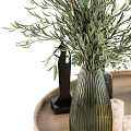 Green Ribbed Vase Holding Olive Branches On Wooden Tray With Black Statue And Candle