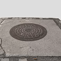 Urban Street Scene With Circular Manhole Cover On Cracked Stone Pavement