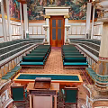 European Architectural Interior with Intricate Mural Ceiling Marble Columns Green Seats and Wooden Podium