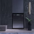 Sleek Black Washing Machine Against Dark Stone Wall With Green Plant
