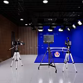 Public Office Space With Dark Blue Wall Wooden Panels White Flooring Cameras Tripods And Lighting