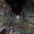 Scenic Tunnel Interior With Rocky Walls Distant Light And Stone Floor