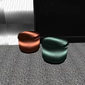 Sleek Modern Copper And Green Sofa Stools On Gray Carpet Against Dark Backdrop