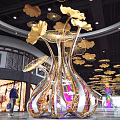 Large Gold And Silver Metal Art Installation With Golden Leaves Purple Light In Mall Interior