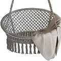 Natural Wicker Hanging Chair With Tassel Trim And Soft Green Blanket Accent