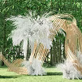 Bamboo Pergola with Curved Design Decorated with White Plants Surrounded by Green Bamboo and Grass