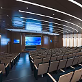 Modern Spacious Conference Room With Rows Of Seats Large Screen And Curved Ceiling Lights
