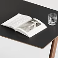 Modern Desk With Black Top Wooden Legs Brown Leather Chair Open Book And Glass Cup