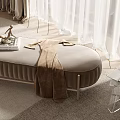 Beige Upholstered Oval Ottoman with Brown Blanket on Top Near White Curtains and Transparent Table