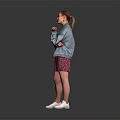 A Woman In Gray Jacket And Pink Floral Skirt Standing On Dark Background With White Sneakers