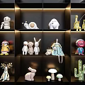 Various Decorative Dolls With Animal And Plant Designs Arranged On Illuminated Black Shelves
