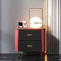 Stylish Nightstand With Red Quilted Sides Two Drawers Gold Handles Round Lamp And Photo Frames On Top