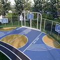 Outdoor Basketball Court With Blue Yellow Surface Track Trees Fence And Signs