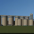 Industrial Plant Featuring Large Silos Green Lawn And Blue Sky With White Clouds