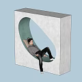 Man in plaid shirt lying in oval hole of white concrete block on wooden floor