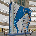 Indoor Rock Climbing Wall With Colorful Holds For Fitness Workout People Climbing In Mall