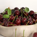 Fresh Ripe Cherries in Ceramic Bowl with Green Leaves and Scattered Berries