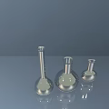 Industrial Equipment Laboratory Silver Flasks in Different Sizes on Smooth Gray Reflective Surface