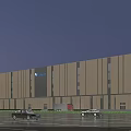 Modern Industrial Factory Building With Large Glass Facade Illuminated At Night And Cars Passing By